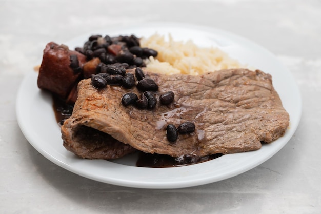 Carne frita con frijoles y arroz hervido en el plato de cerámica