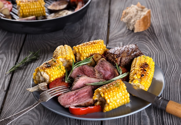 Foto carne frita y maíz con verduras en un plato