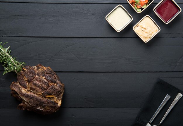 Carne frita con verduras, salsa y salsa sobre un fondo de madera negra