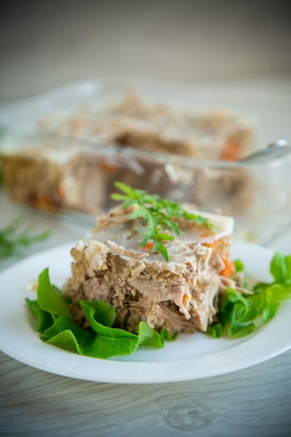 Carne en gelatina con verduras y verduras en un plato sobre una mesa de madera