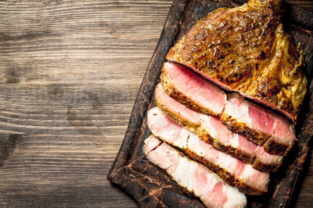 Carne grelhada com especiarias em uma placa de corte. Em uma mesa de madeira.