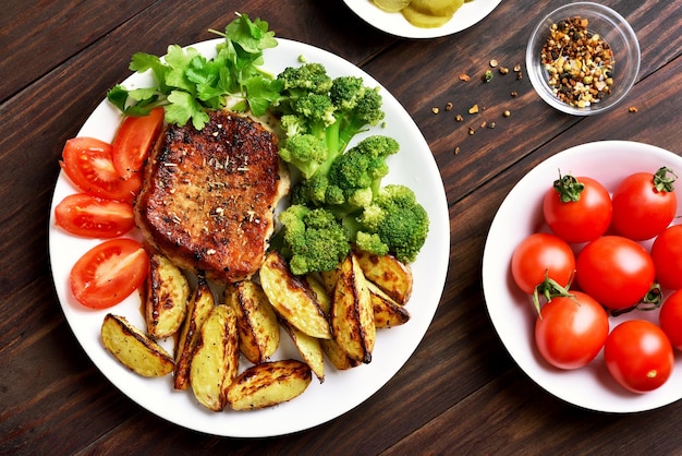 Carne grelhada com vegetais em prato sobre fundo de madeira vista superior