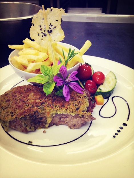 Carne grelhada e batatas fritas servidas num prato