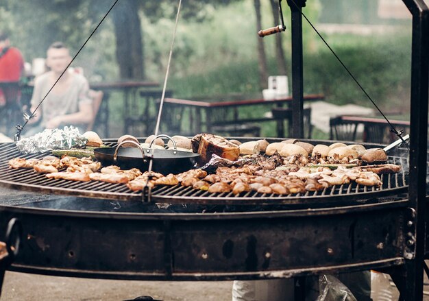 Carne grelhada e legumes cogumelos assando carne de porco na grelha grande cozinha aberta festival de comida de rua cozinhar costelas suculentas defumadas batatas churrasco e pão piquenique de verão