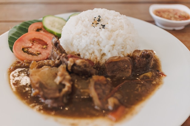 Carne guisada tailandesa con arroz servido en plato blanco