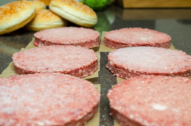 Carne de hamburguesa congelada en la mesa antes de asar a la parrilla, descongelar antes de asar.