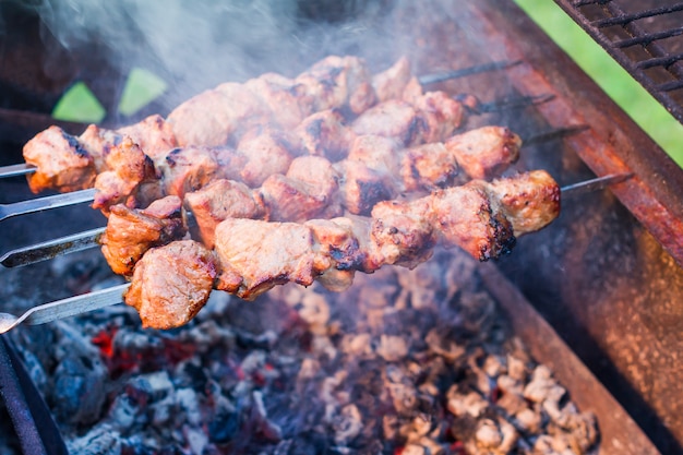 Carne marinada grelhada em espetos. Shashlik russo. Pratos tradicionais. Churrasqueira ao ar livre no quintal.