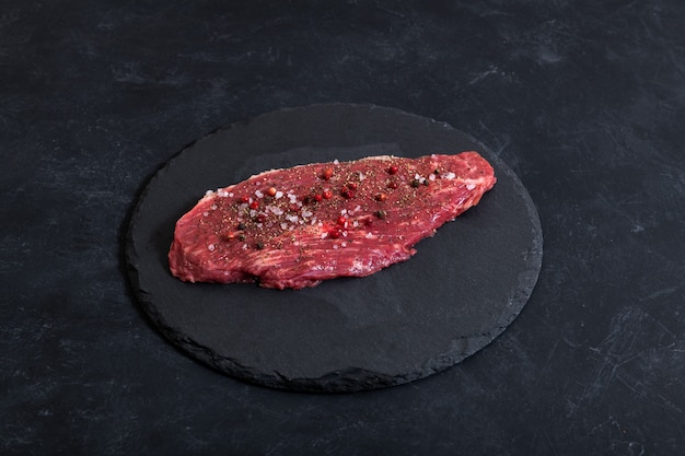 Carne marmolada fresca cruda y condimentos en la parte superior de ckground oscuro compiten