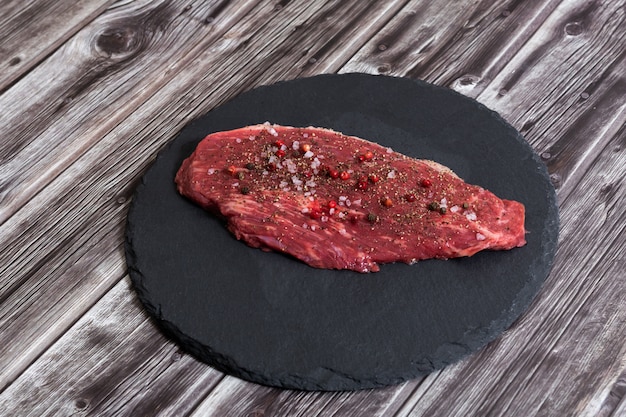 Carne marmorizada fresca crua e temperos na parte superior escura do ckground vie