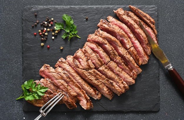 Carne média. Bife grelhado com ervas provençais em uma placa de pedra.