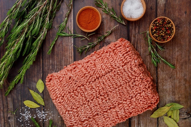 Carne moída com especiarias e alecrim na mesa de madeira.