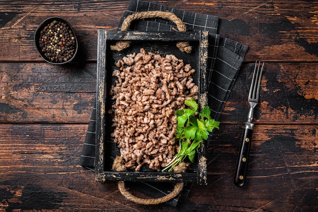 Carne moída frita e carne de cordeiro em uma bandeja de madeira com ervas Fundo de madeira Vista superior