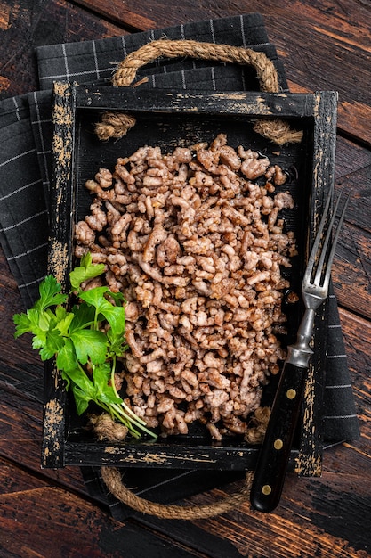 Carne moída frita e carne de cordeiro em uma bandeja de madeira com ervas Fundo de madeira Vista superior