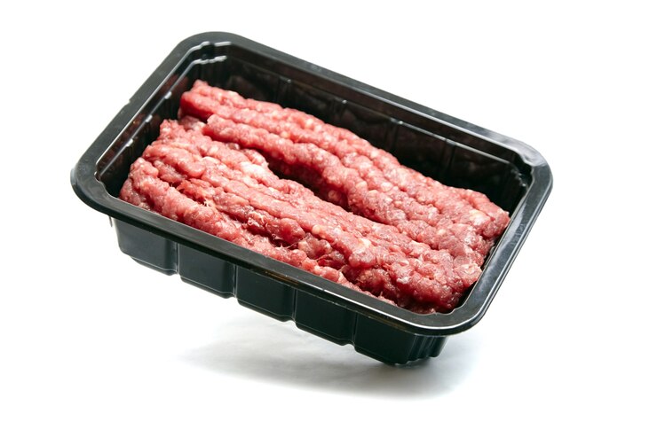 Carne molida en una bandeja de plástico negro aislado sobre fondo blanco. Carne picada sin cocer. Carne picada, carne picada fresca cruda
