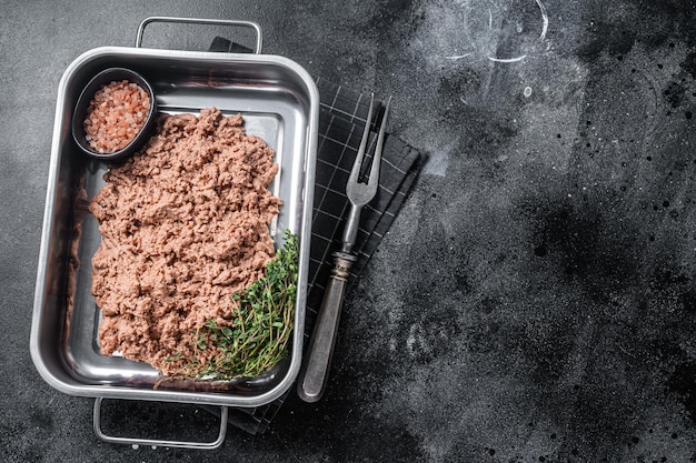 Carne molida vegetariana carne cruda a base de plantas con hierbas en bandeja de cocina Fondo negro Vista superior Espacio de copia