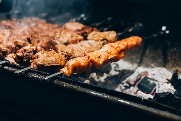 Carne no espeto. grelha de porco. churrasco de fumar na rua. cozinhar frango shashlik. brasas.