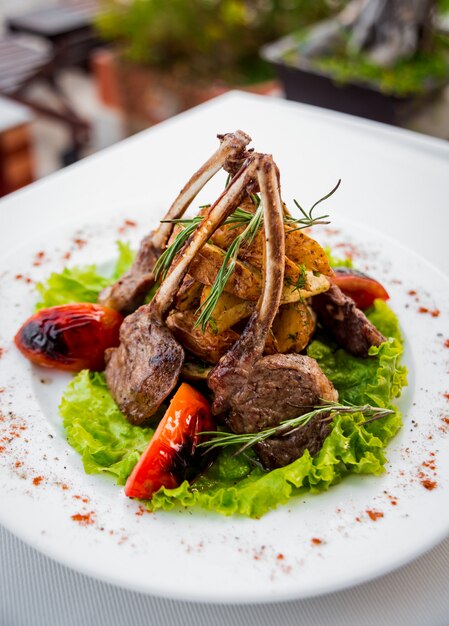 Carne no osso com legumes em um prato branco. Restaurante.