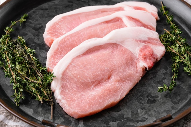 Carne orgânica crua. Bifes de porco, filés para grelhar, no fundo da mesa de pedra branca