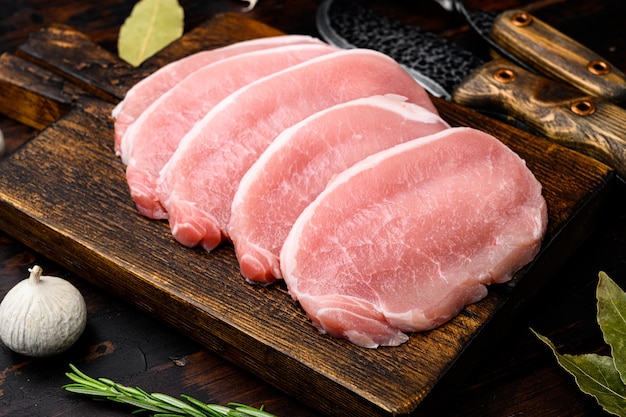 Carne orgánica cruda. Filetes de cerdo, filetes para asar, hornear o freír, sobre fondo de mesa de madera oscura.