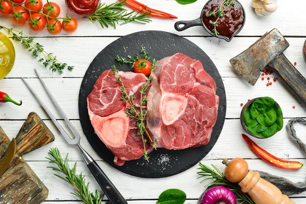 Foto carne osso buco filete de ternera con romero y especias sobre un fondo blanco de madera vista superior