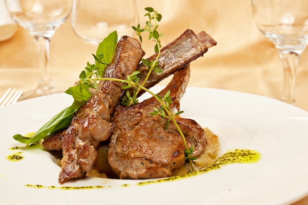 Carne de oveja asada con huesos en plato en restaurante.