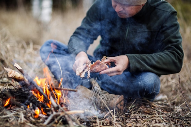 Carne en el palo a la parrilla en el concepto de bushcraft de fuego