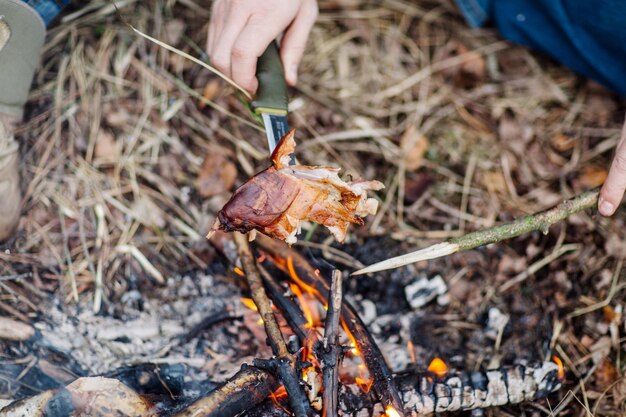 Carne en el palo a la parrilla en el concepto de bushcraft de fuego