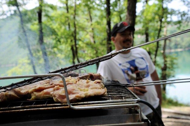 Carne a la parrilla en la parrilla de la barbacoa Concepto de fiesta de picnic de cena Fondo de comida a la parrilla Un hombre sonriente en el fondo