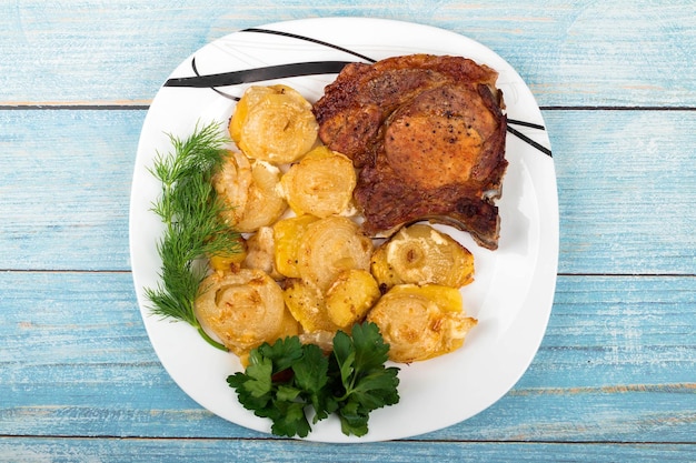 Carne a la parrilla con verduras y hierbas en un plato de fondo de madera azul