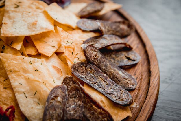 Carne y patatas fritas en un plato de madera con cerveza.