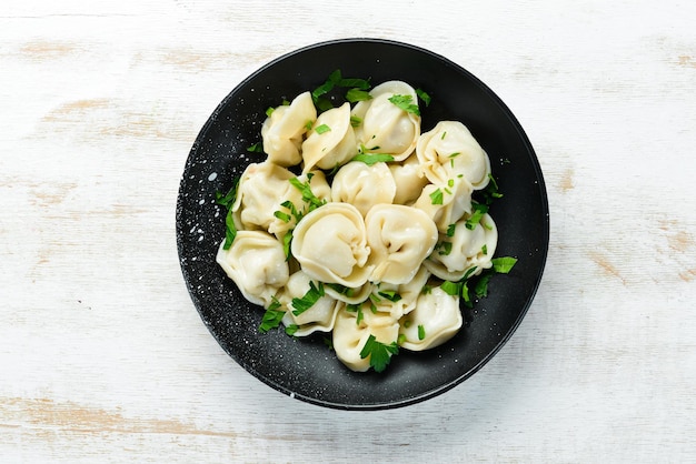 Carne pelmeni rusa Albóndigas con verduras en un plato negro Cocina tradicional rusa Vista superior Espacio de copia libre