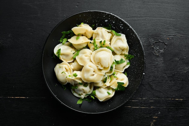 Carne pelmeni rusa Albóndigas con verduras en un plato negro Cocina tradicional rusa Vista superior Espacio de copia libre