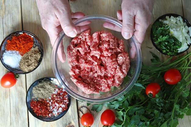 Carne picada en un bol y las manos del cocinero.