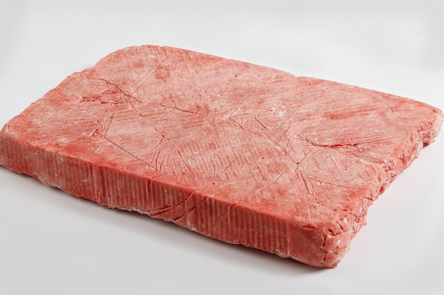 Foto carne picada congelada sobre un fondo blanco.