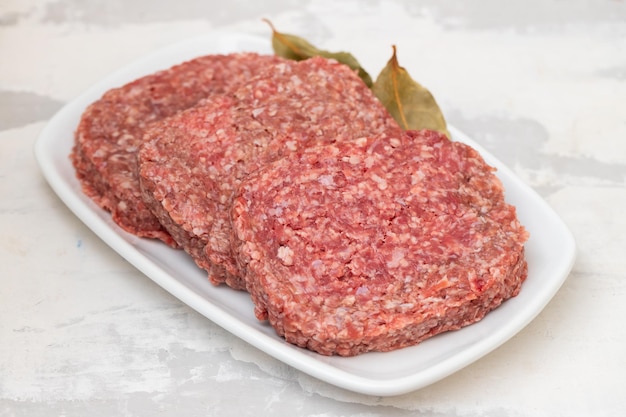 Carne picada crua fresca no prato branco com folha de louro