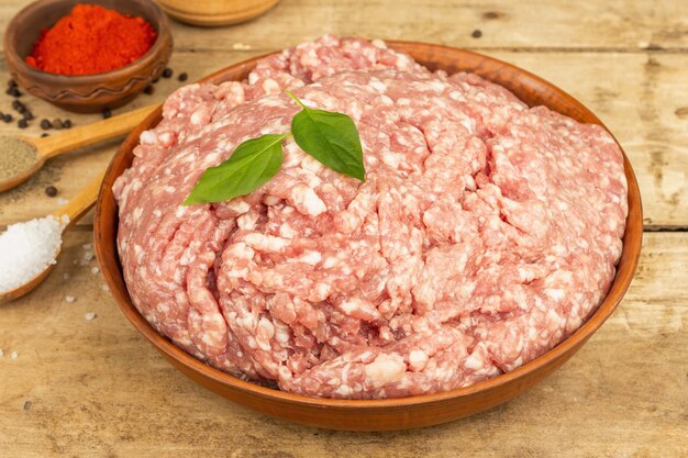 Carne picada cruda. Carne de cerdo molida con especias, aceite de cocina. Mesa de madera antigua, cerrar