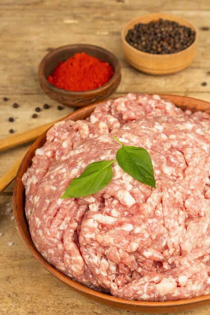 Carne picada cruda. Carne de cerdo molida con especias, aceite de cocina. Mesa de madera vieja, vista superior