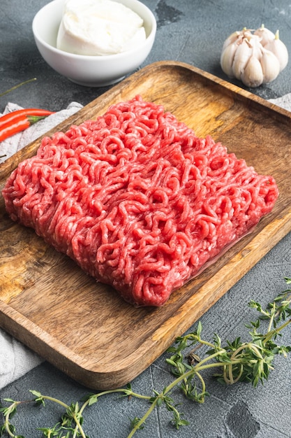 Carne picada cruda con especias, verduras y hierbas y albóndigas, sobre fondo de piedra gris