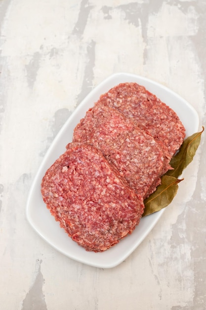 Carne picada cruda fresca en plato blanco con hoja de laurel