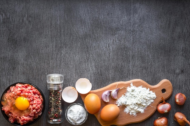 Carne picada cruda con yema de huevo, tabla de cortar de madera sobre fondo de madera