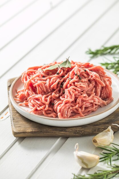 Carne picada de carne crua fresca com ervas e alecrim na placa de madeira em um lugar de receita de menu de banner de fundo leve para vista superior de texto