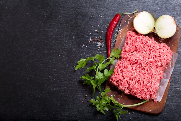 Carne picada con verduras en tablero oscuro