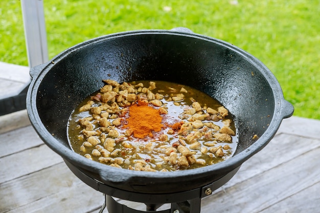 Carne y pimentón rojo cocinar en caldero en fuego plato al aire libre