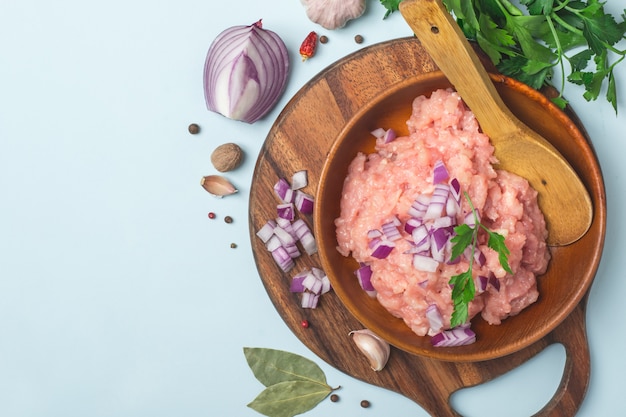 Carne de pollo cruda picada en un tazón con especias