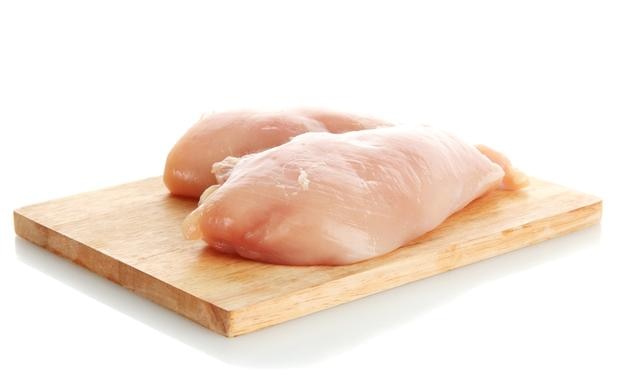 Carne de pollo cruda en tabla de cortar aislada en blanco