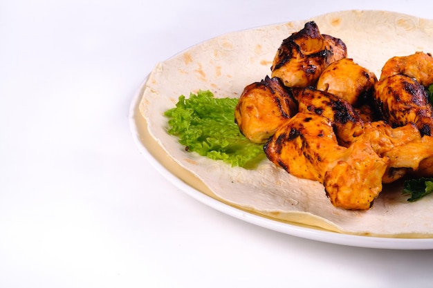 Carne de pollo en pan de pita con verduras en un plato blanco sobre un fondo blanco aislado.