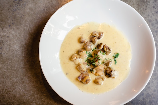 Foto carne de rapana frita en salsa de queso y crema sobre un fondo blanco en un restaurante gourmet