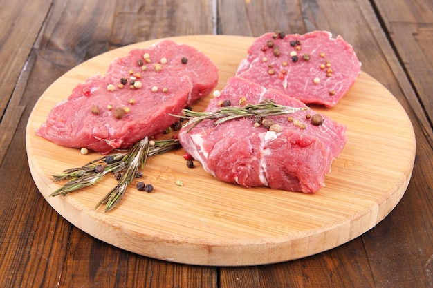 Carne de res cruda con especias en tabla de cortar sobre fondo de madera