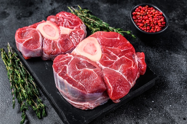 Carne de res cruda filete de caña de osso buco, ossobuco italiano. Fondo negro. Vista superior.