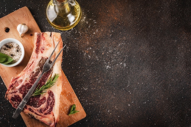 Carne de res cruda, marmoleada, filete de costilla, filete de costilla con especias, hierbas en la tabla de cortar